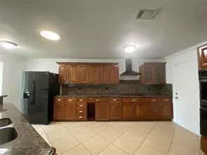 a large kitchen with granite countertop a refrigerator and a sink