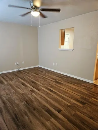 a view of an empty room with window and wooden floor
