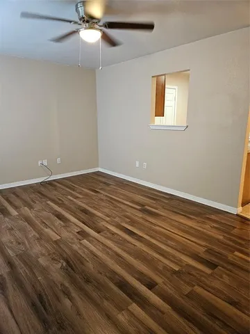 a view of an empty room with window and wooden floor