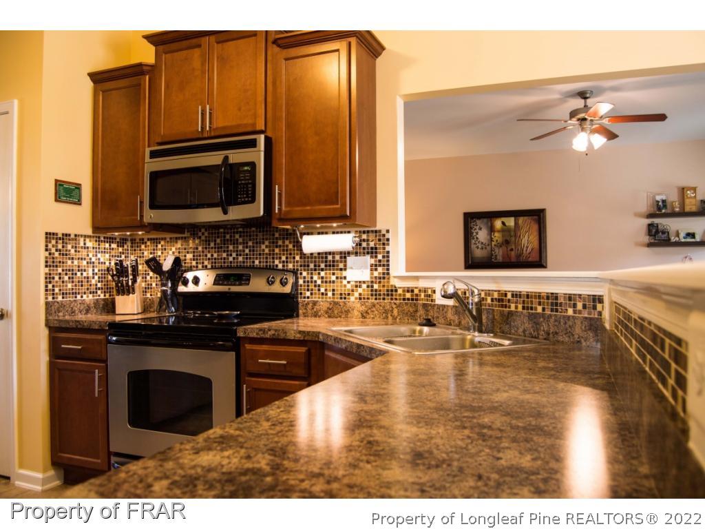 1444 Rough Rider Lane Parkton, NC 28371 - Photo 15 of 36 a kitchen with stainless steel appliances granite countertop a stove a sink and a microwave