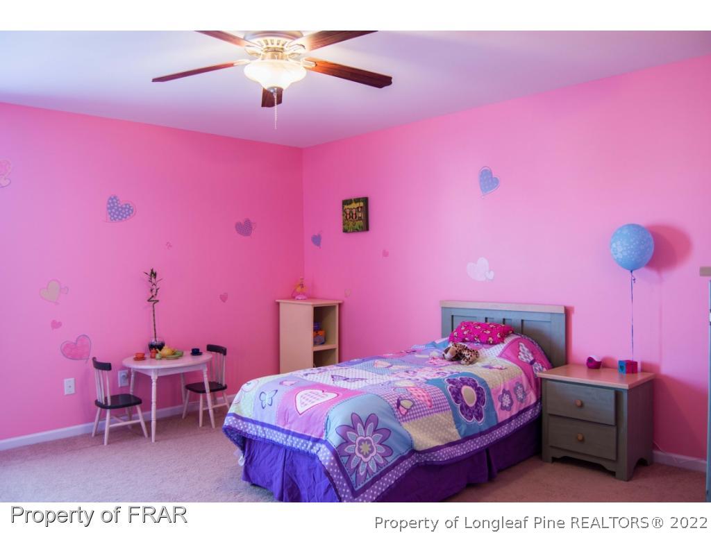 1444 Rough Rider Lane Parkton, NC 28371 - Photo 26 of 36 a bedroom with a bed a chandelier and pink walls