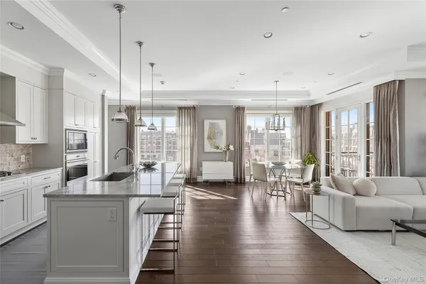 a living room with stainless steel appliances granite countertop furniture a couch a large window and wooden floor