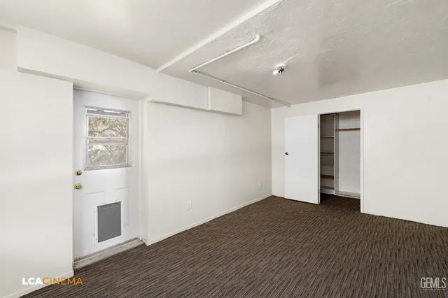 a view of an empty room with wooden floor and a ceiling fan