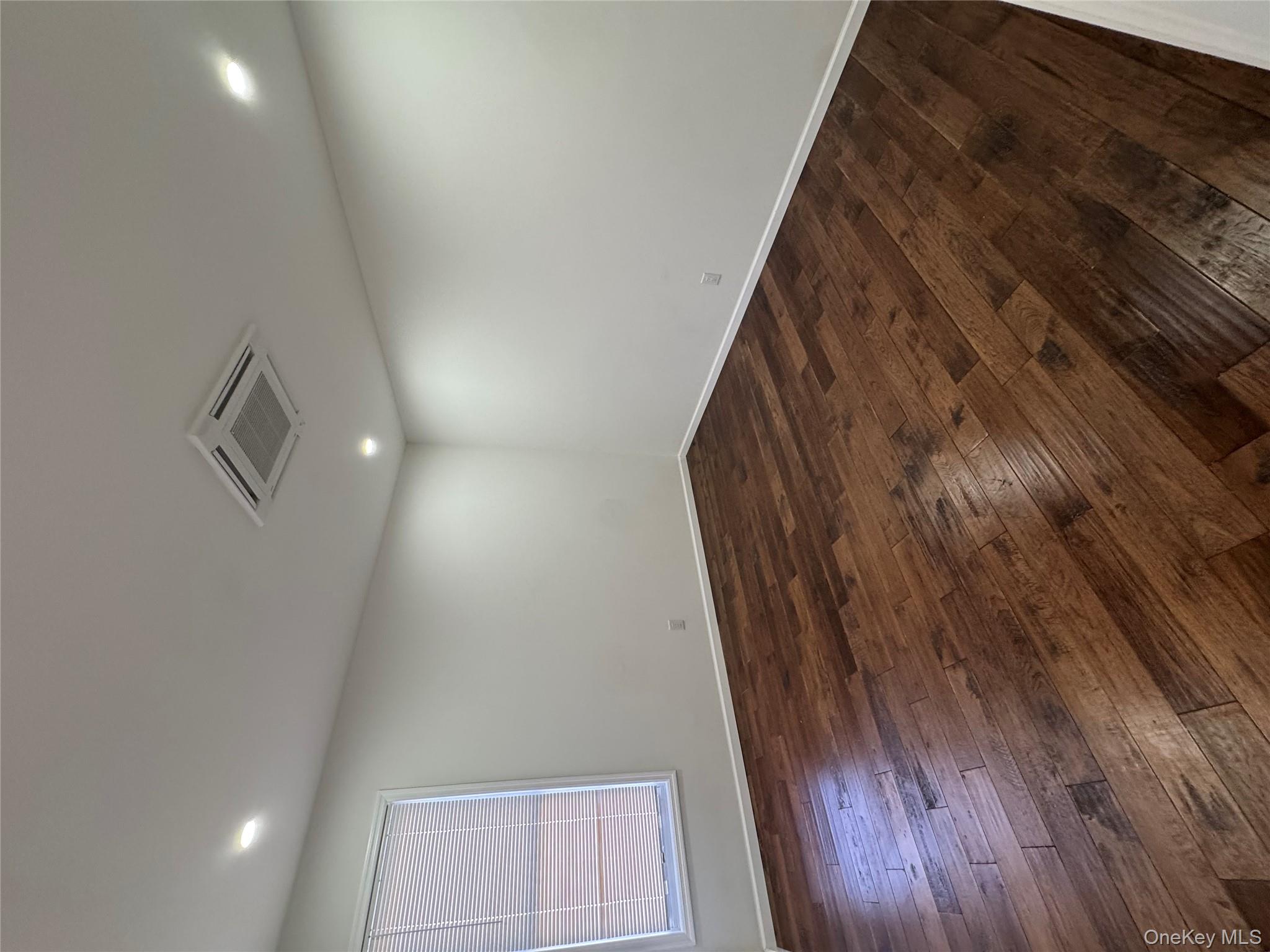 88-36 77th Street Queens, NY 11421 - Photo 7 of 19 an empty room with wooden floor and windows
