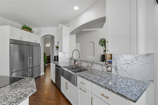 a kitchen with stainless steel appliances granite countertop a sink a refrigerator and a counter space