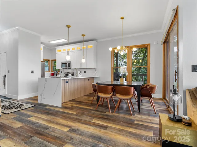 a kitchen with kitchen island granite countertop a stove a refrigerator a dining table and chairs with wooden floor