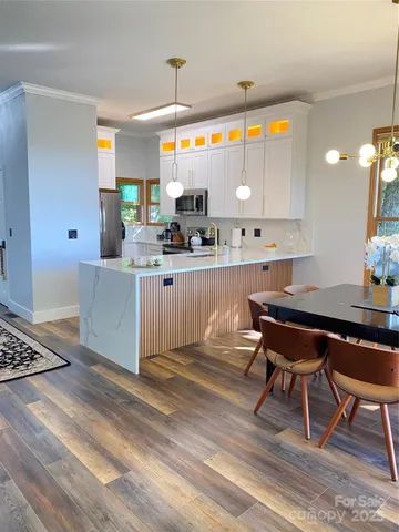 a kitchen with stainless steel appliances kitchen island granite countertop a table chairs sink and cabinets