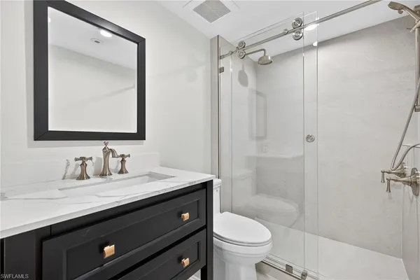 a bathroom with a granite countertop sink toilet a mirror a vanity and shower