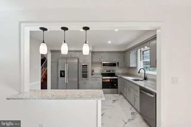 a large kitchen with granite countertop a large kitchen island and stainless steel appliances