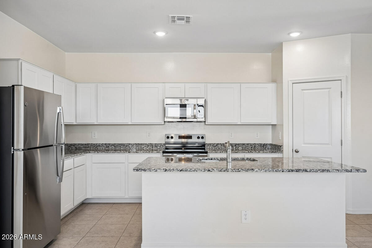 31690 Rodeo Road San Tan Valley, AZ 85140 - Photo 25 of 35 a kitchen with a refrigerator a stove top oven and white cabinets