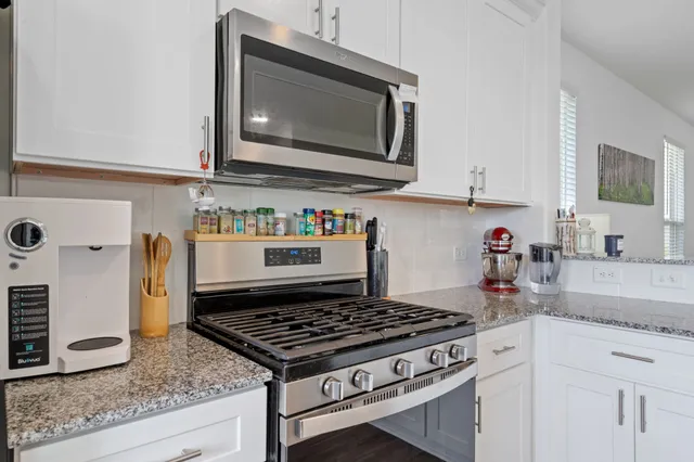 a kitchen with stainless steel appliances granite countertop a sink stove and microwave