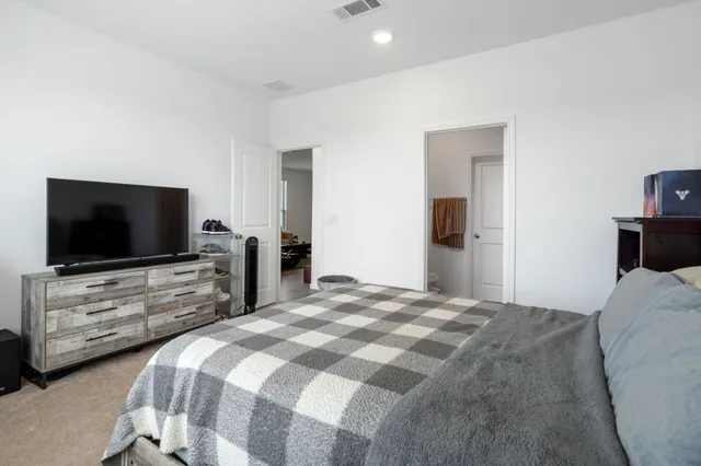 a bedroom with a bed and a flat screen tv in white walls