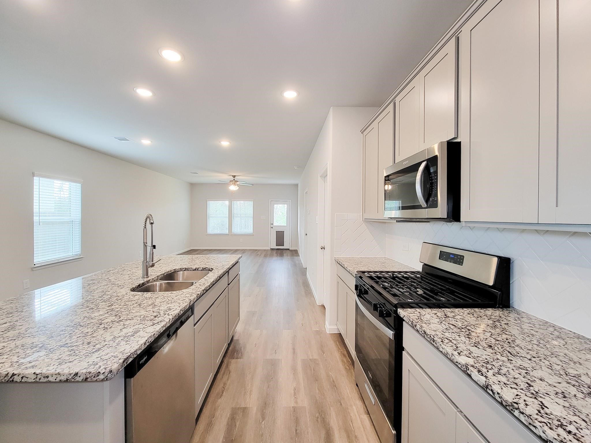 94 Valiant Ridge Trail Magnolia, TX 77354 - Photo 17 of 47 a kitchen with granite countertop kitchen island stainless steel appliances a sink stove top oven and cabinets