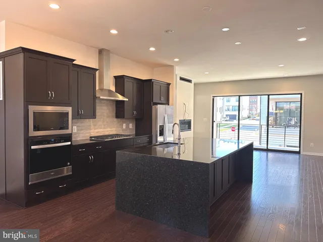 a kitchen with stainless steel appliances granite countertop a refrigerator a sink dishwasher stove and oven with wooden cabinets