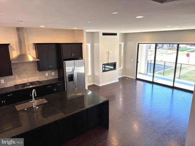 a kitchen with stainless steel appliances granite countertop a refrigerator a sink a stove and wooden floor