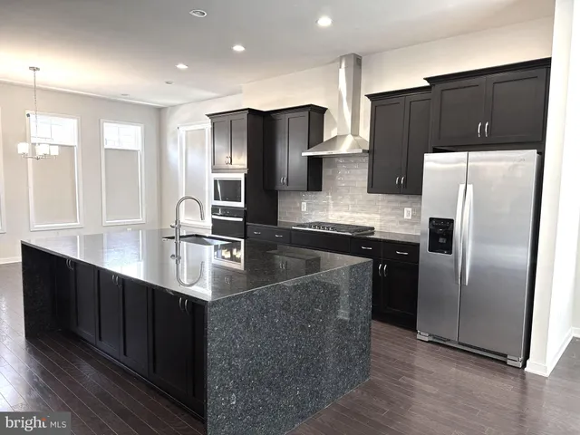 a kitchen with stainless steel appliances granite countertop a refrigerator a sink a stove a oven with wooden floor