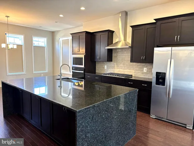 a kitchen with stainless steel appliances granite countertop a refrigerator a sink and wooden cabinets