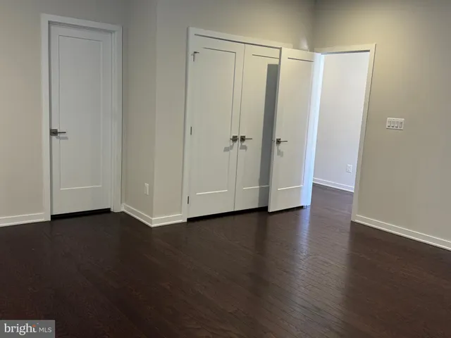 a view of an empty room with wooden floor and closet