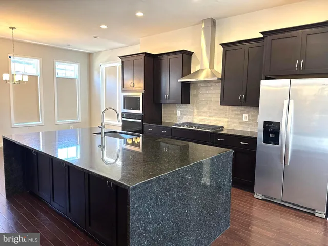 a kitchen with stainless steel appliances granite countertop a refrigerator a sink and wooden cabinets