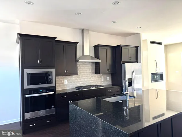 a kitchen with stainless steel appliances granite countertop a sink a stove and a refrigerator