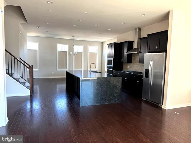 a kitchen with stainless steel appliances granite countertop a refrigerator a stove and a wooden floors