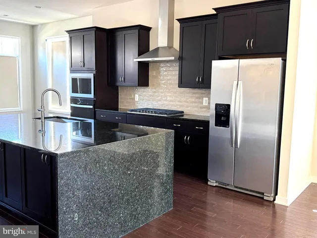 a kitchen with stainless steel appliances granite countertop a refrigerator and a stove