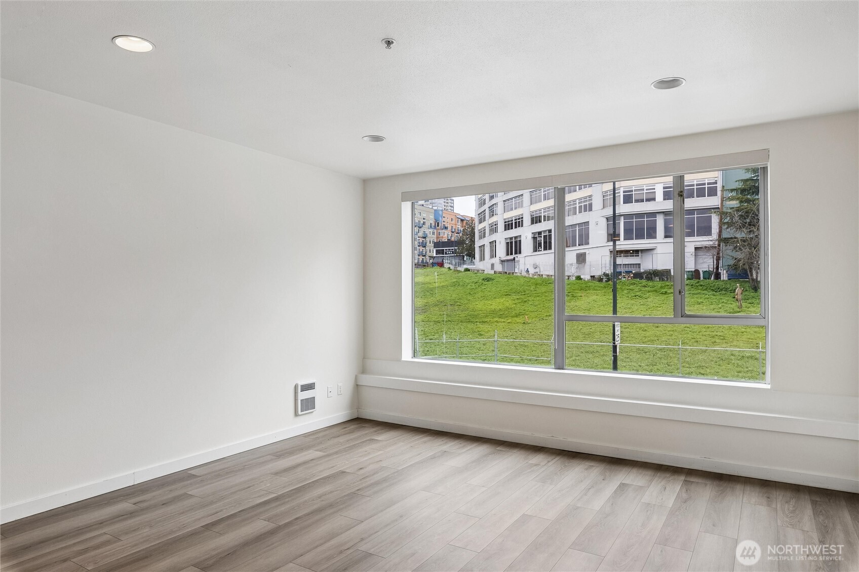66 Bell Street, Unit 23 Seattle, WA 98121 - Photo 1 of 24 a view of an empty room with wooden floor and a window