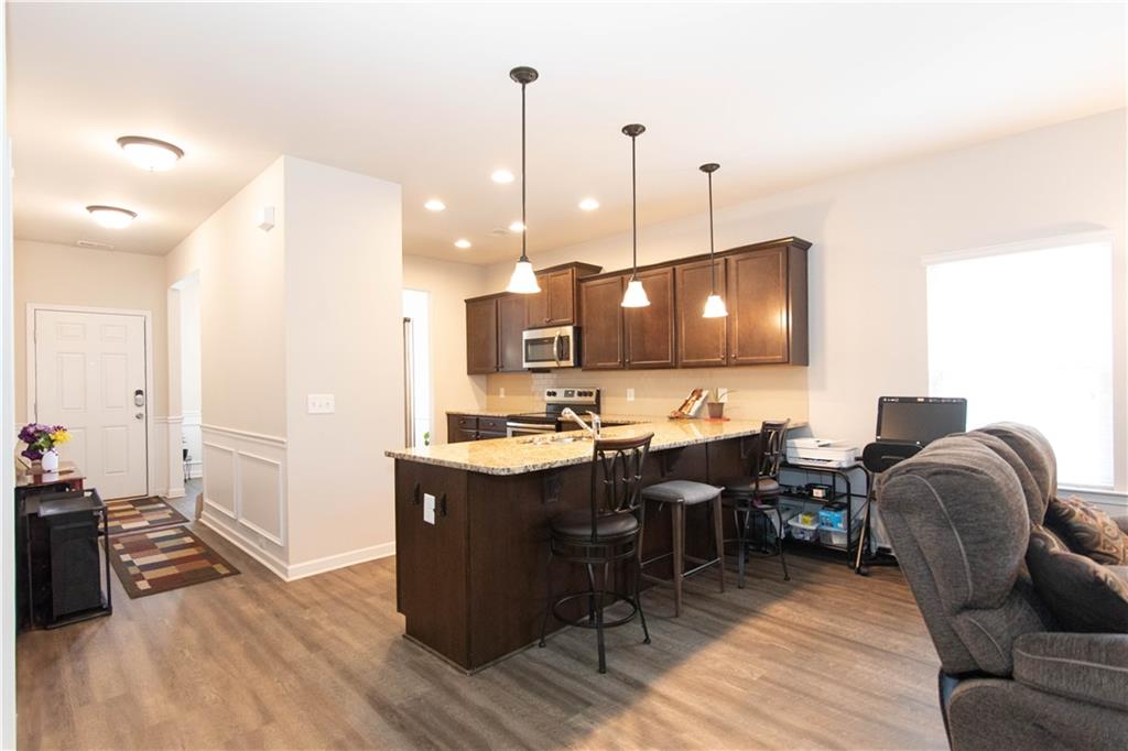 103 Prominence Court Canton, GA 30114 - Photo 11 of 34 a living room with stainless steel appliances kitchen island granite countertop a stove a sink a refrigerator and blue cabinets with wooden floor