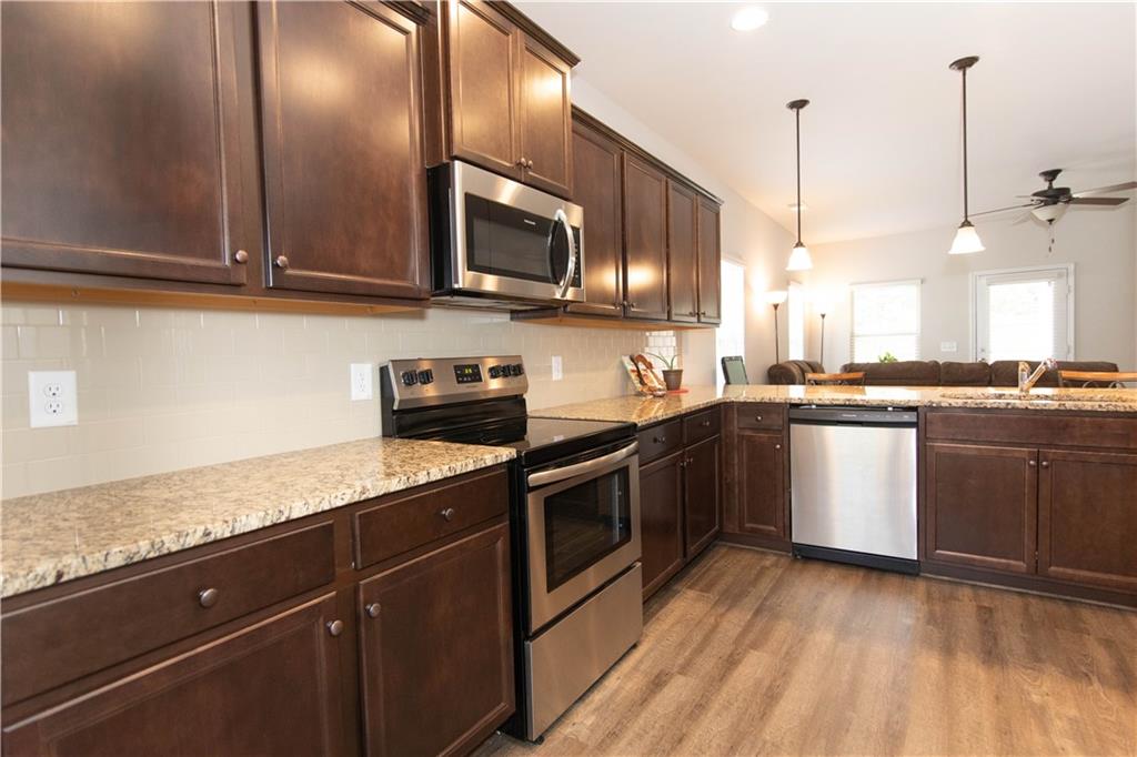 103 Prominence Court Canton, GA 30114 - Photo 6 of 34 a kitchen with stainless steel appliances granite countertop a sink a stove and microwave with wooden floor