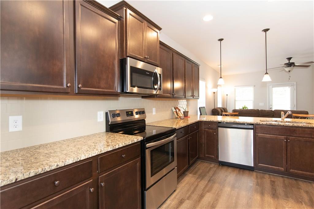 103 Prominence Court Canton, GA 30114 - Photo 10 of 34 a kitchen with stainless steel appliances granite countertop a sink a stove top oven and wooden floor