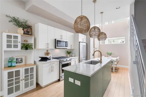 a kitchen with kitchen island granite countertop a sink a stove and cabinets