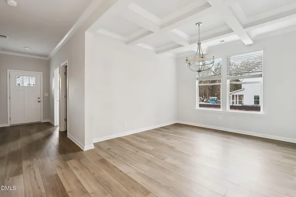 an empty room with wooden floor chandelier and windows
