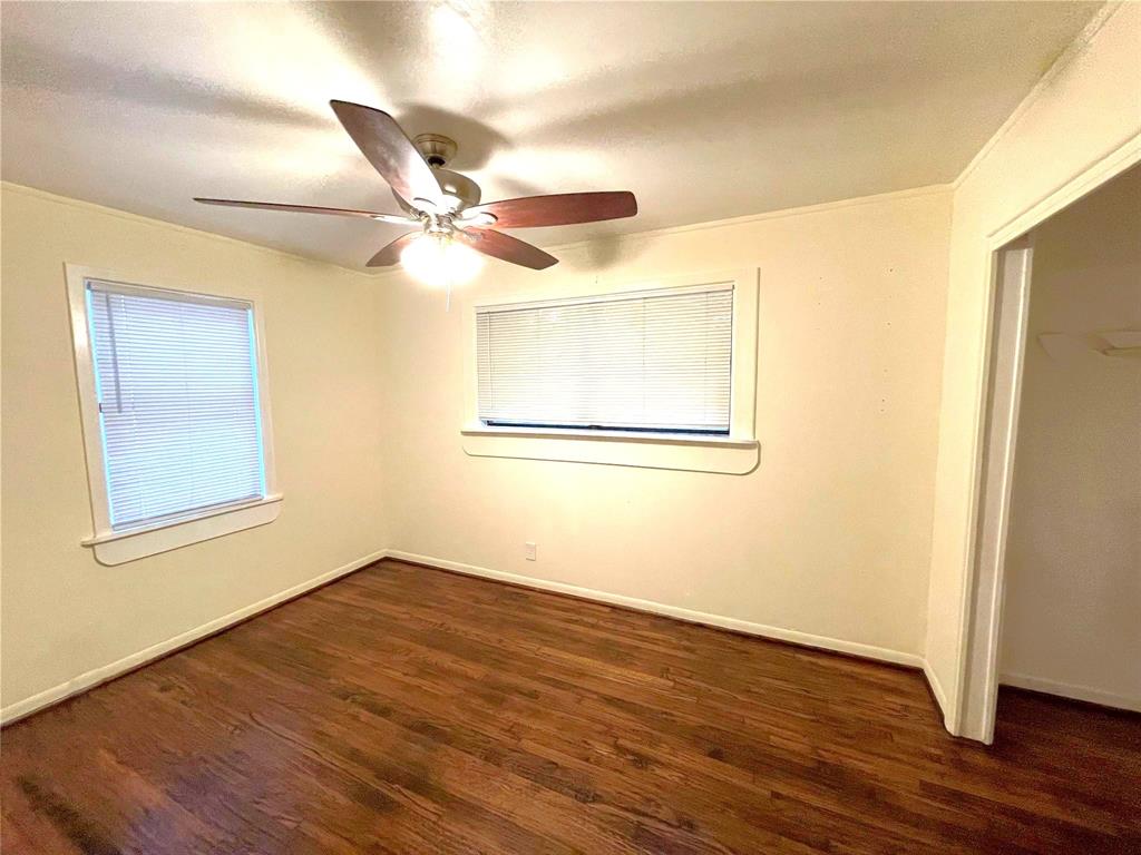 501 South Perry Avenue Denison, TX 75020 - Photo 7 of 11 Room featuring wood-finish flooring, two windows with blinds, a ceiling fan with integrated lighting, and closet