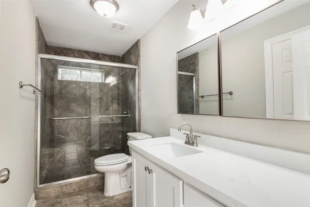 a bathroom with a sink a toilet and shower