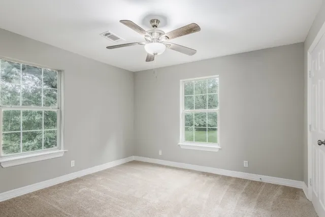 an empty room with windows and ceiling fan