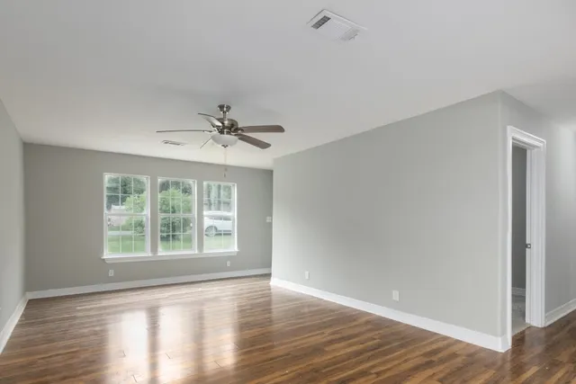 a view of an empty room with wooden floor and a window