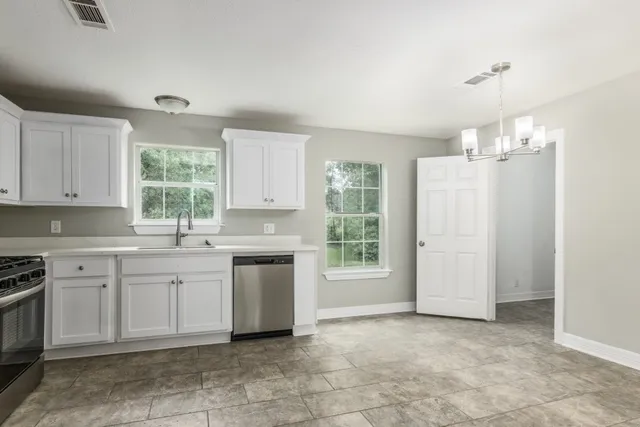 a kitchen with a stove a sink dishwasher a refrigerator and white cabinets