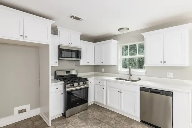 a kitchen with cabinets stainless steel appliances a sink and a window