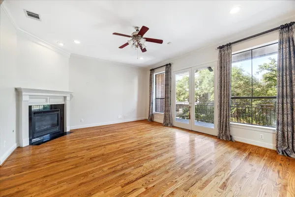 a view of an empty room with wooden floor fireplace and a window