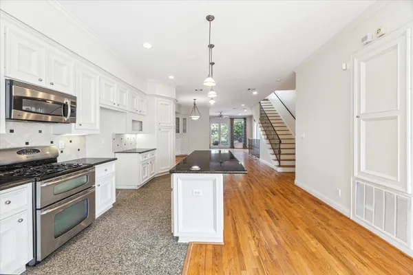 a kitchen with stainless steel appliances kitchen island granite countertop a sink a stove top oven a counter space and cabinets