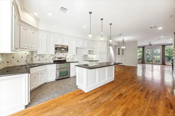 a large kitchen with granite countertop a white stove top oven and white cabinets