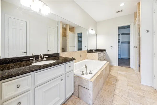 a spacious en suite bathroom with a granite countertop sink and mirror