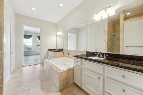 a spacious bathroom with a granite countertop sink a mirror and a bathtub