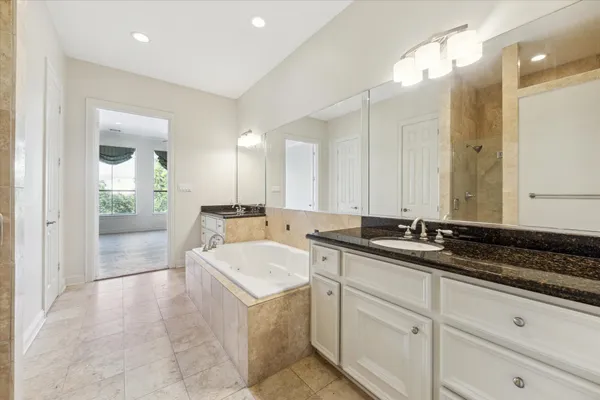 a spacious bathroom with a granite countertop sink a mirror and a bathtub