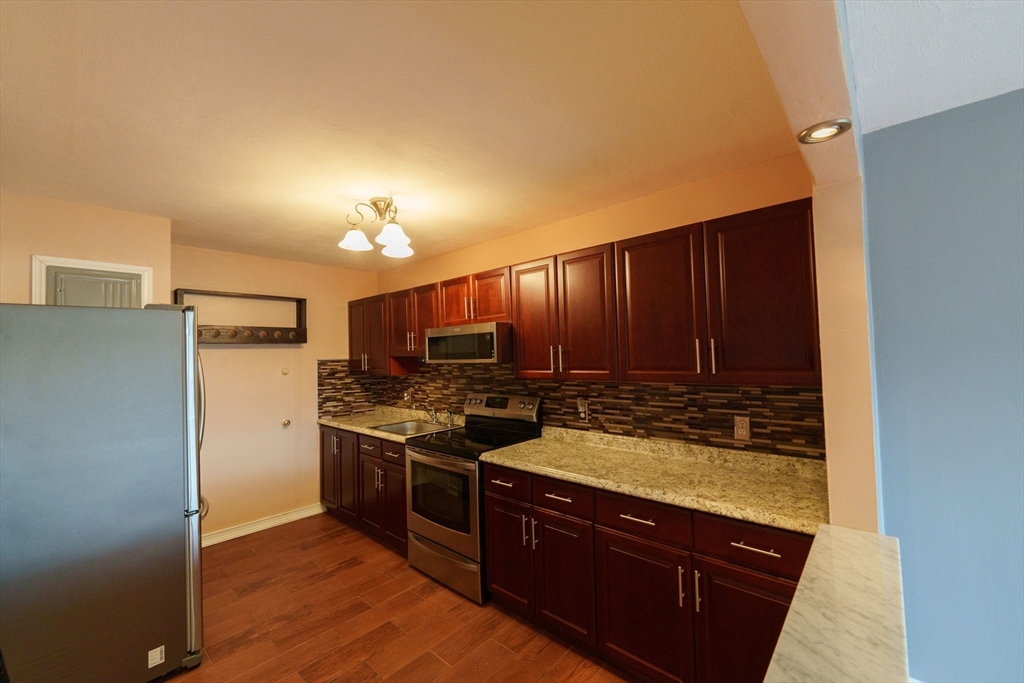 a kitchen with stainless steel appliances granite countertop a stove a refrigerator and a sink with wooden cabinets