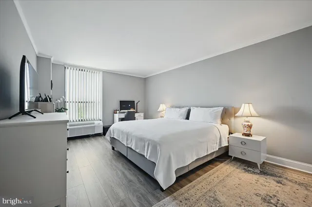 a bedroom with a bed lamp on desk and a window
