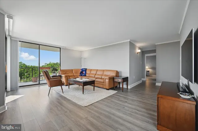 a living room with furniture a large window and wooden floor
