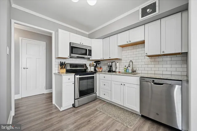 a kitchen with granite countertop a refrigerator stove top oven and sink