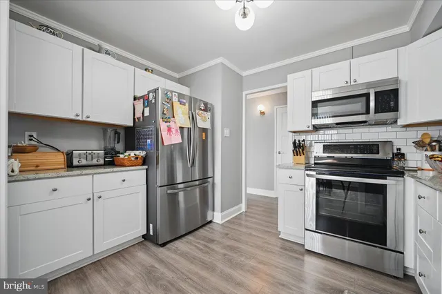a kitchen with stainless steel appliances granite countertop a refrigerator stove and white cabinets
