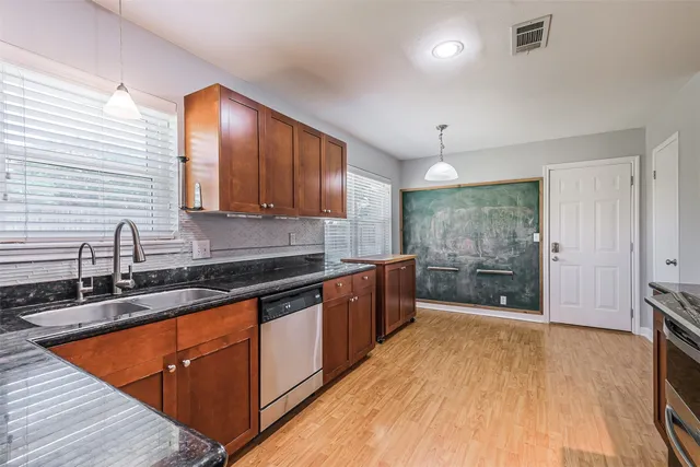 a kitchen with stainless steel appliances granite countertop a sink a stove and a wooden floors